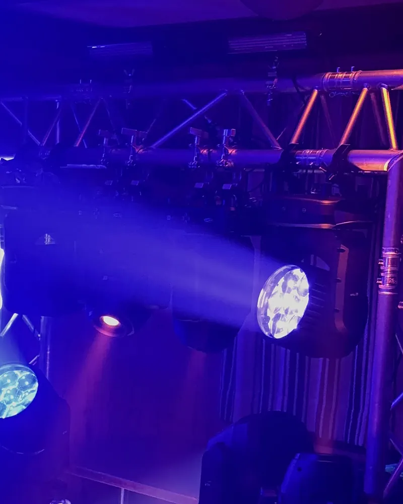 Moving Heads mit blauen Lichtstrahlen an einer Traverse